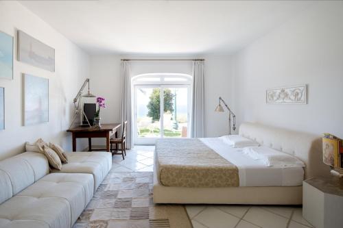 Luxury Relais Villa Magdalena في ايسكيا: غرفة نوم بيضاء مع سرير وأريكة
