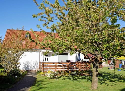 a white house with a tree in the yard at Ferienhaus an der Granitz in Seerams