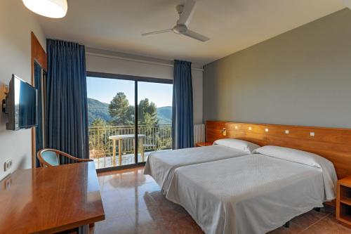 a bedroom with a bed and a large window at Can Fisa Hotel & Apartments in Corbera de Llobregat