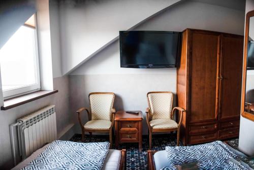 a bedroom with two chairs and a bed and a tv at Stacja Jura in Kroczyce