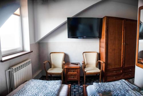 1 Schlafzimmer mit 2 Stühlen, einem Bett und einem TV in der Unterkunft Stacja Jura in Kroczyce