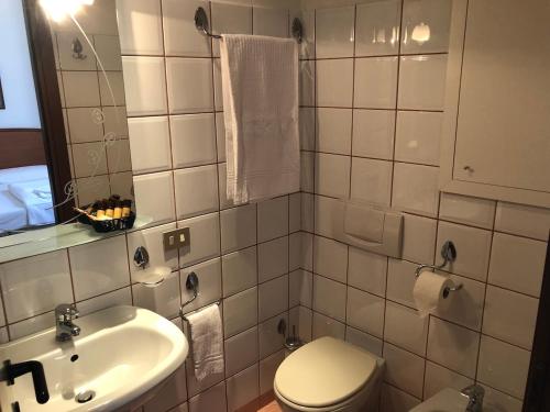 La salle de bains blanche est pourvue de toilettes et d'un lavabo. dans l'établissement Hotel Saini, à Stresa