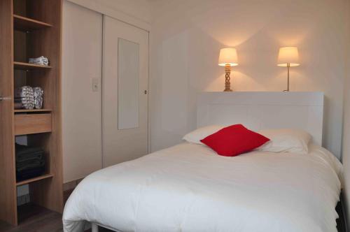 a bedroom with a white bed with a red pillow at Appartement cosy refait à neuf au coeur de Saint Nazaire à 300m du front de mer in Saint-Nazaire