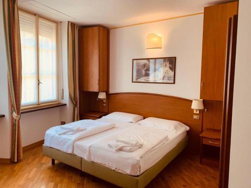 ストレーザにあるホテル サイニのベッドルーム1室(木製ヘッドボード付きのベッド1台付)