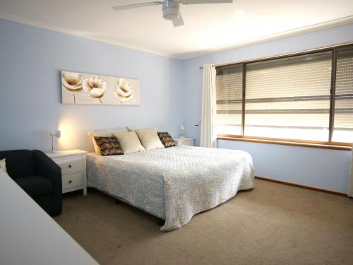 a bedroom with a bed and a chair and a window at Salty Air Apartments Kingscote Kangaroo Island in Kingscote