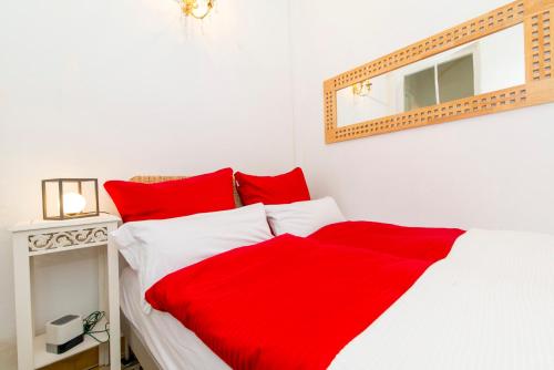 Cama blanca con sábanas rojas y espejo en Charming town house just 500m from the marina and its well known typical market en Olhão