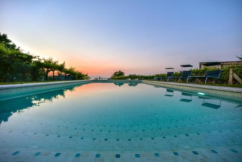 a swimming pool with chairs and a sunset in the background at Casa Vilar in Sanxenxo