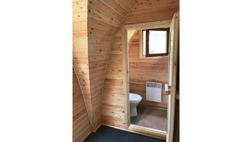 a bathroom in a log cabin with a toilet at Glamp V Hluboké - Yurts and Wooden Houses in Vsetín