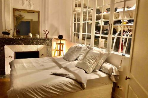 een wit bed in een kamer met een open haard bij 5 min place Stanislas. Appartement de caractère in Nancy