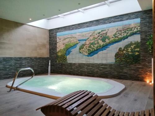 uma banheira de hidromassagem num quarto com um mural em Hotel Rural & SPA Puente del Duratón em Sepúlveda