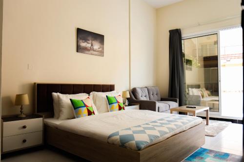 a bedroom with a bed and a chair and a window at SHH - Furnished Studio in Knight Bridge Court A, JVC in Dubai