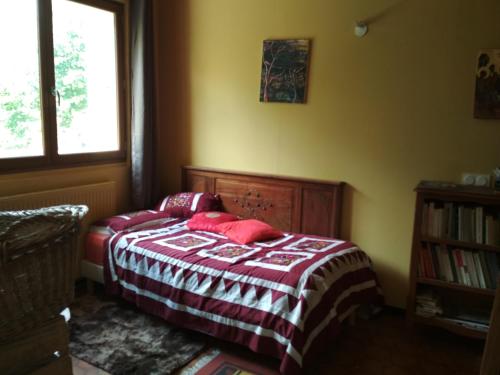 Schlafzimmer mit einem Bett mit roten Kissen und einem Fenster in der Unterkunft Daphrose chambre in Lachau
