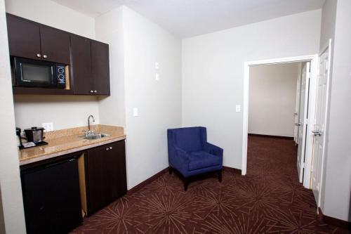 a kitchen with a blue chair in a room at La Quinta by Wyndham Houston East at Normandy in Houston