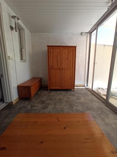 pusty pokój z drewnianą szafką i drzwiami w obiekcie Appartement à Marseillan plage accès direct à la plage w mieście Marseillan