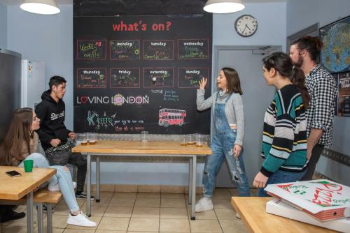 a group of people standing around a table in a room at Astor Victoria Hostel in London