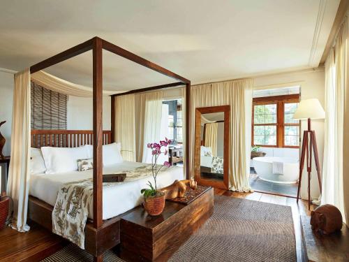 a bedroom with a large canopy bed and a bathroom at Santa Teresa Hotel Rio de Janeiro - MGallery Collection in Rio de Janeiro