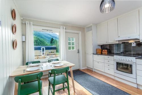 a kitchen with a table and two green chairs at Two bedroom apartment in beautiful Flåm valley in Flåm