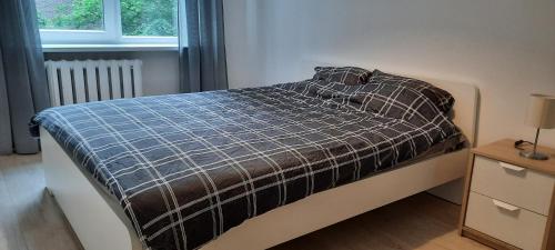 um quarto com uma cama com um cobertor xadrez e uma janela em Excellent Rest 2 rooms em Klaipėda