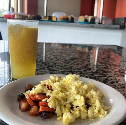 a plate of scrambled eggs and a glass of orange juice at HOTEL AVENIDA in Alta Floresta