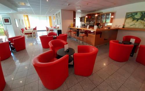 a restaurant with red chairs and a table and a bar at Lenas West Hotel in Vienna