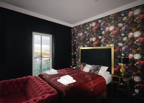 a bedroom with a red bed and a floral wall at Prymasa Tysiąclecia 83A by Homeprime in Warsaw