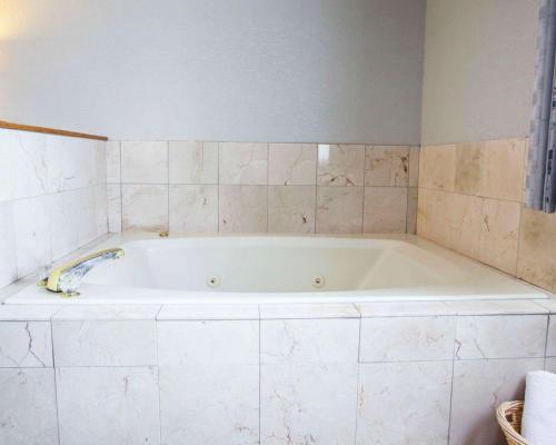 a white bath tub in a bathroom with tiles at Quality Inn & Suites Ankeny-Des Moines in Ankeny