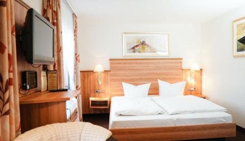 een slaapkamer met een bed en een flatscreen-tv bij Neckarblick SELF Check IN Hotel in Bad Wimpfen
