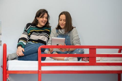 two women sitting on a bed with a laptop at Astor Victoria Hostel in London