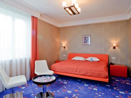 オリョールにあるGRINN HOTEL & SPAのベッドルーム(赤いベッド1台、白い椅子付)
