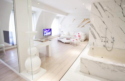 a white bathroom with a tub and a living room at Boscolo Nice Hotel & Spa in Nice