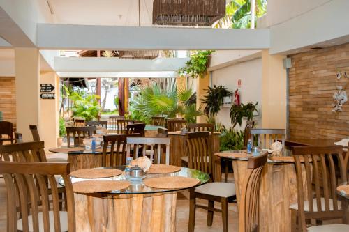 un restaurante con mesas de madera, sillas y plantas en Jeri Village Hotel, en Jericoacoara