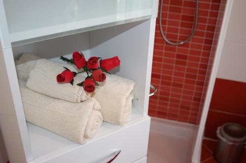 a bathroom with towels and roses on a shelf at Le Margherite in Cardano al Campo
