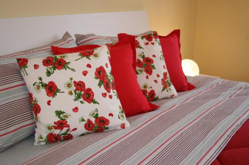 a bed with red and white pillows on it at Le Margherite in Cardano al Campo