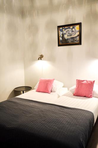 a bedroom with a bed with two pink pillows at Family Hotel Kooyk in Amsterdam
