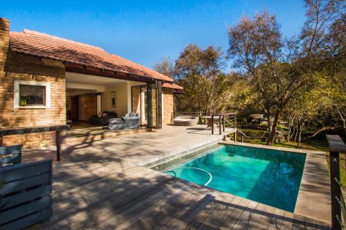 a patio with a swimming pool and a house at Riverdance in Komnader