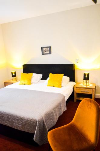 a bedroom with two beds with yellow pillows and a chair at Family Hotel Kooyk in Amsterdam