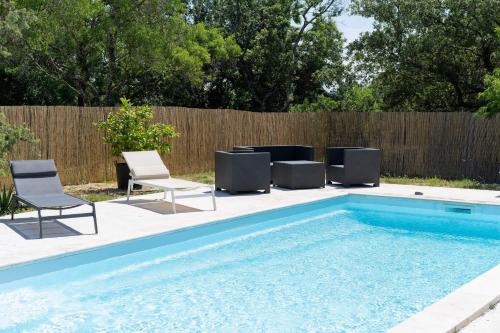 a swimming pool with chairs and a fence at Le Mas du Berger in Saint-Quentin-la-Poterie