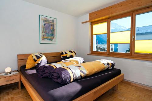 un letto con cuscini sopra in una stanza con finestre di Wieser - Ferienwohnung für 2-3 Personen a Sent