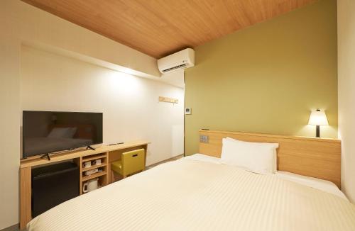 a hotel room with a bed and a flat screen tv at Sotetsu Fresa Inn Tokyo Tamachi in Tokyo