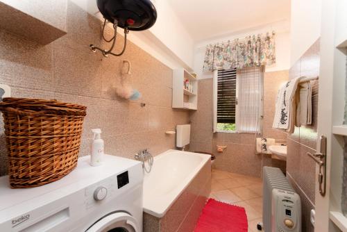a bathroom with a tub and a washing machine at Apartment Nigra in Lovran