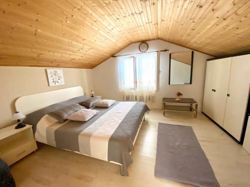 a bedroom with a large bed with a wooden ceiling at Guesthouse Kurelic Rab in Kampor