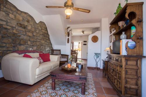 a living room with a white couch and a stone wall at La Casita De Ana in Jimena de la Frontera