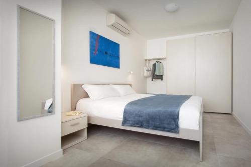 a white bedroom with a bed and a mirror at LA ROCCA SUITE in Garda