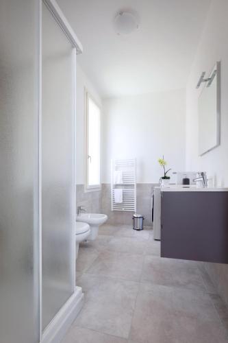 a white bathroom with a sink and a toilet at LA ROCCA SUITE in Garda