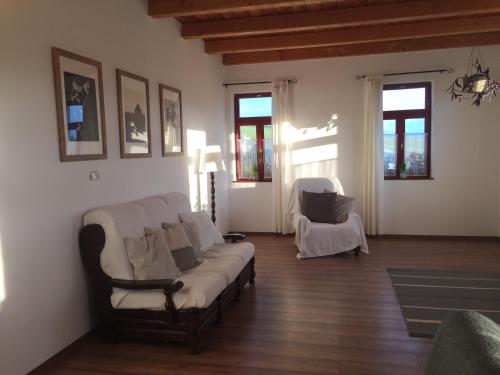 a living room with a couch and two windows at Dósa tanya, Vendégház in Cserépfalu