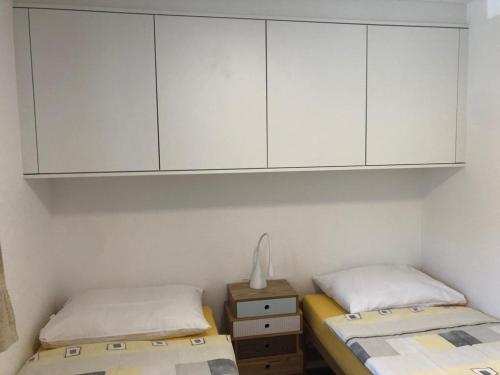- 2 lits dans une chambre avec des armoires blanches dans l'établissement Haus Allod 201 Gretler, à Lenzerheide