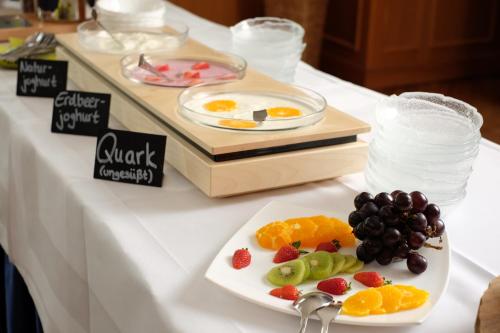 a white table with a plate of fruit on it at Hotel Restaurant Clemens-August in Ascheberg