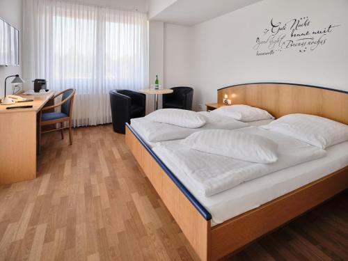 a bedroom with a large bed with a desk and a desk at Hotel Restaurant Clemens-August in Ascheberg