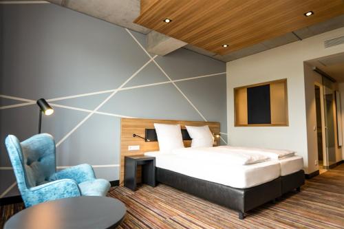 um quarto de hotel com uma cama e uma cadeira em N+S City Hotel Neumarkt em Neumarkt in der Oberpfalz