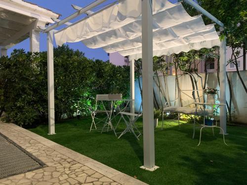 a white pergola with chairs and a table in a yard at White House Luxury Hospitality in Olbia